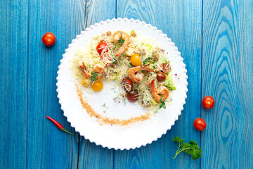 Shrimp salad in a plate. On a blue, wooden background.