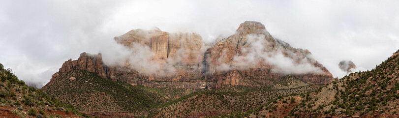 Fototapeta premium Panorama of the mountains of Zion National Park in Utah with a heavy overcast and clouds dramatically passing in from of the peaks. This unusual weather provides a dramatic feel and a sense of calm.