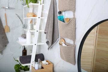 Knitted organizer hanging on wall in bathroom - obrazy, fototapety, plakaty