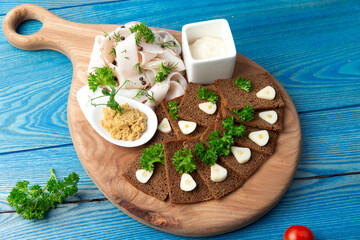 Chopped bacon, garlic croutons on a board. On a blue, wooden background.