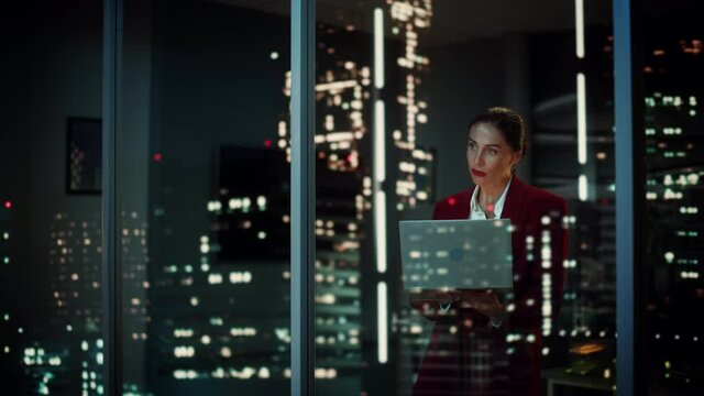 Successful Businesswoman in Stylish Suit Working, on Laptop Looking in Wonder at Night City. Stylish Beautiful Female CEO Working Late on Computer to Achieve Best Results. Colorful Cinematic Portrait