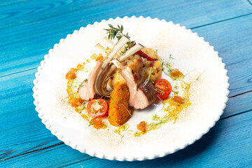 Lamb rack in a plate. On a blue wooden background.