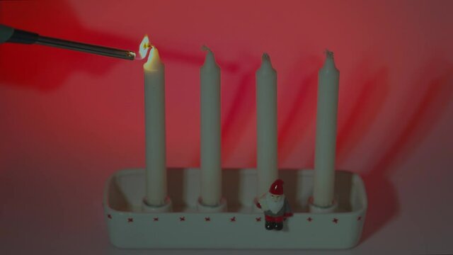 Close up view of man lights first candle in traditional candlesticks of  first advent on a red background. 
Sweden.