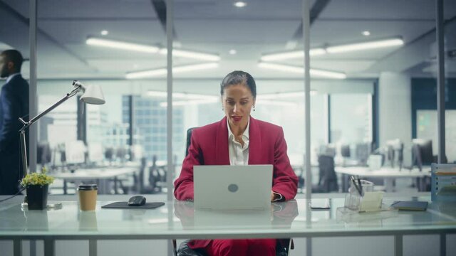 Successful Caucasian Businesswoman in Perfectly Stylish Suit Working on Laptop Computer on Top Floor Office Overlooking Big City. Female CEO Managing Company. Front View Static Medium Shot