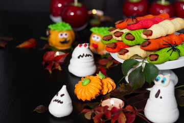 Obraz na płótnie Canvas Enchanting array of Halloween-themed desserts, with ghoulish meringue spirits and vibrant marzipan pumpkins, on a mysterious dark backdrop.