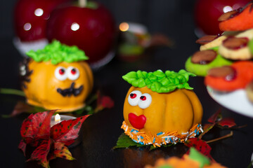 Alluring Halloween confections featuring meringue apparitions, cheerful marzipan fruits, and glossy apples, set against a shadowy background.