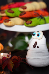 Mesmerizing meringue ghost with expressive blue eyes takes center stage among a delectable spread of Halloween cookies and autumn leaves.