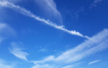 Blue summer sky, vapor trails and white clouds