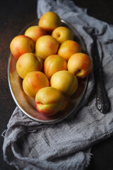 Yellow nectarines on oval plate with gray kitchen cloth