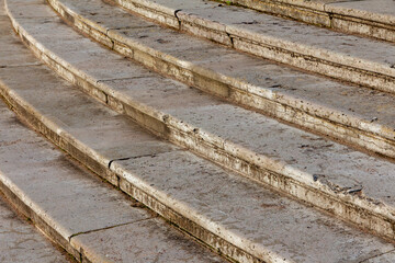 Old stone semicircular staircase with caverns on the surface