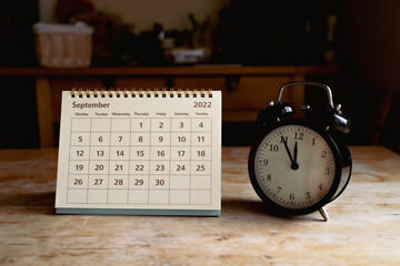 Naklejka premium September 2022 calendar and black vintage clock on wooden table