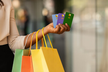 Unrecognizable black female holding three credit cards and shopping bags - Powered by Adobe