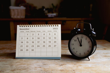 Novwmber 2022 calendar and black vintage clock on wooden table