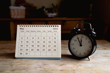 Naklejka premium May 2022 calendar and black vintage clock on wooden table