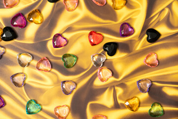 Multicolored glass hearts lie on a golden background.