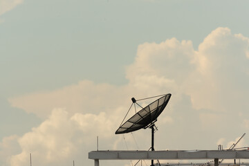 Satellite dish on building deck roof.Satellite receiver on sky and clouds background.