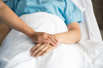 Fototapeta na wymiar Close up doctor taking patients hand on the bed in hospiital.Nurse hand holding patient hand for empowerment.Care giver touching hand patient in clinic.Psychological support concept.