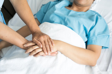 Close up doctor taking patients hand on the bed in hospiital.Nurse hand holding patient hand for empowerment.Care giver touching hand patient in clinic.Psychological support concept.