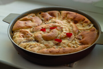 Traditional fragrant apple pie in a round shape with a golden crust on a light table.