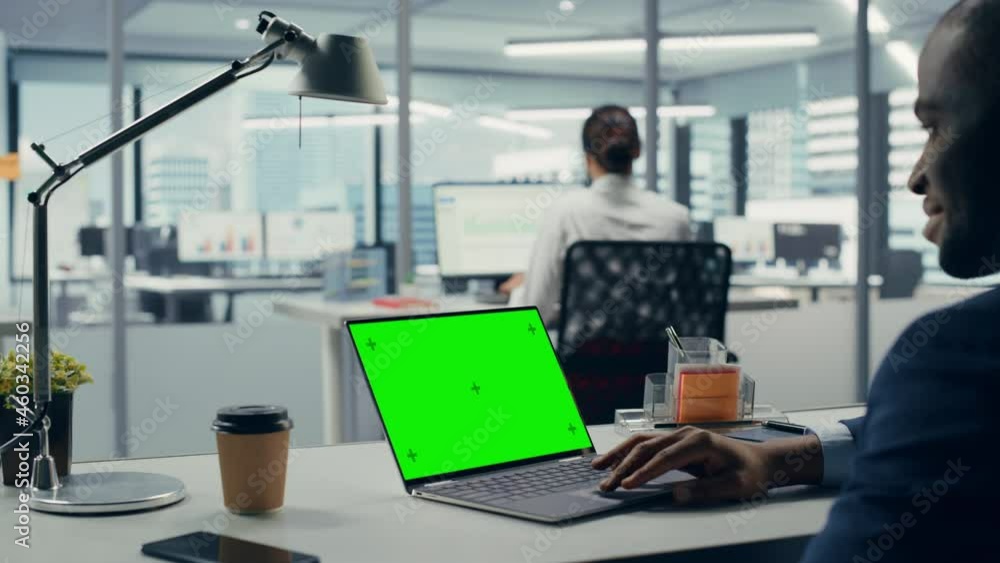 Aufkleber successful black businessman sitting at desk working on green screen chroma key laptop computer in b