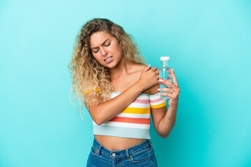 Young blonde woman with a bottle of water isolated on blue background suffering from pain in shoulder for having made an effort