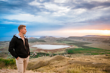 A young man conquered the top of the mountain at dawn. Beautiful mountain landscape with a slope. The concept of enjoying nature.