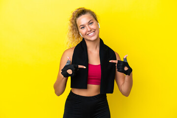 Sport woman with towel isolated on yellow background proud and self-satisfied