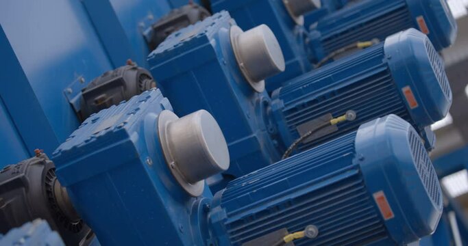 Rows of blue powerful industrial motors in the processing line of a new modern plant 