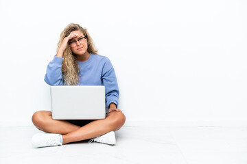 Girl with curly hair with a laptop sitting on the floor looking far away with hand to look something
