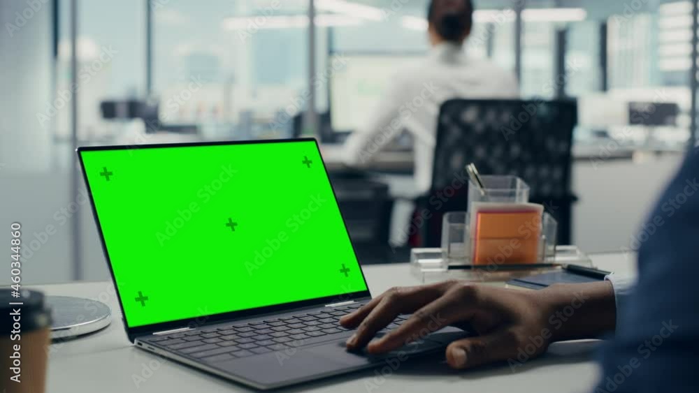 Poster successful black businessman sitting at desk working on green screen laptop computer in office. anon