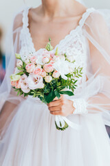 The bride in a white dress holds the bride's bouquet