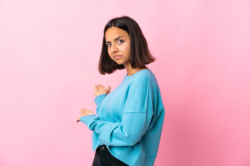 Young latin woman isolated on pink background extending hands to the side for inviting to come