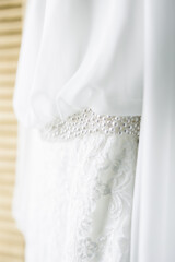 Elements of the bride's white dress. airy chiffon sleeves and embroidery on fabric. The composition is a wedding dress.