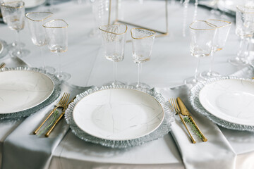 glass glasses and white plates. table setting in the interior of the restaurant. The decor of the...