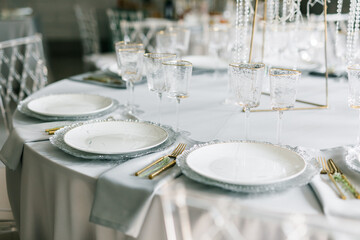 glass glasses and white plates. table setting in the interior of the restaurant. The decor of the...