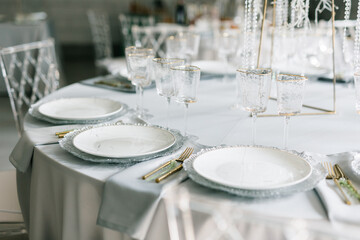 glass glasses and white plates. table setting in the interior of the restaurant. The decor of the...