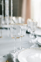glasses of triangular shape on a set table. Plates and glasses are placed on the table. Festive table decor