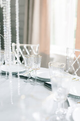 glass glasses and white plates. table setting in the interior of the restaurant. The decor of the festive table. In gray-silver tones with gold cutlery. Luxury wedding, party, birthday.