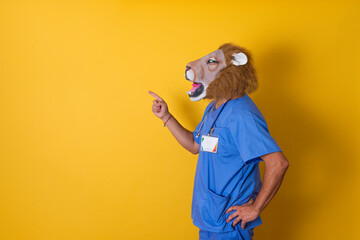 Doctor in profile with lion mask and stethoscope pointing to copy space with yellow background.