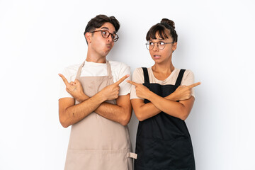 Restaurant mixed race waiters isolated on white background pointing to the laterals having doubts