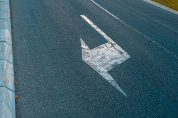 White arrow sign painted on asphalt turn right on the asphalt road