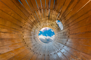 Wooden circle tube with cloudy sky at the end