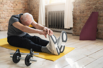 Active elderly man stretching during his fitness workout at home