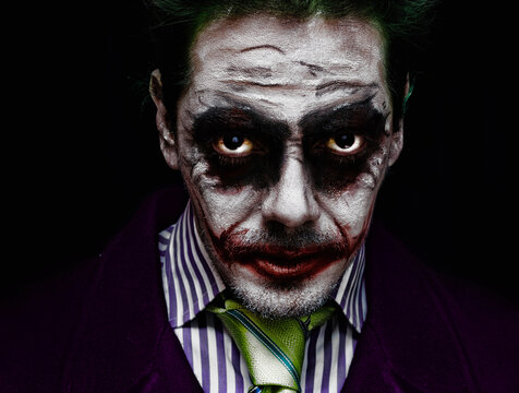 Portrait of a man with makeup looking like the joker. Halloween makeup dark scary concept. Mysterious Costume