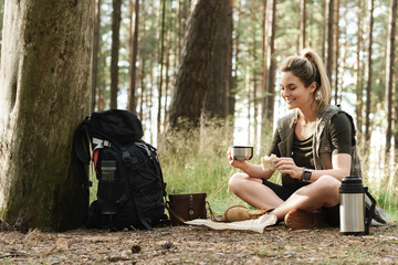 Fototapeta premium Female hiker during small halt eating sandwich in green forest