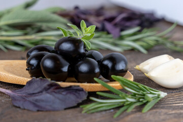 olives with spices and rosemary in a wooden spoon