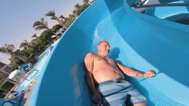 Selfie of funny man sliding on toboggan on waterslide in aquapark