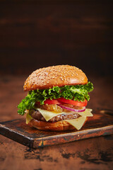 Homemade burger with beef, cheese and onion marmalade on a wooden board. Fast food concept, american food