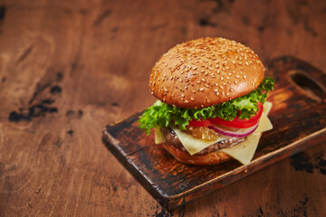Homemade burger with beef, cheese and onion marmalade on a wooden board. Fast food concept, american food