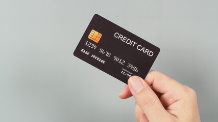 Hand is holding black credit card isolated on grey background.